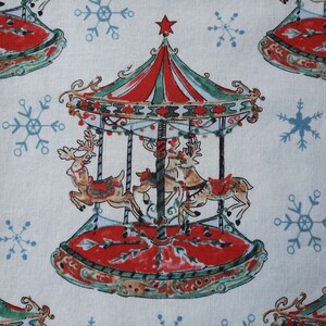 May include: A white fabric with a repeating pattern of red, green, and white carousel horses with a red, green, and white striped canopy. The background is white with a blue snowflake pattern.