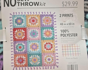 May include: A no sew throw kit featuring a 100% polyester anti-pill fleece blanket with a purple, teal, and white floral pattern. The packaging includes a label showing a 48 in x 60 in finished size with a multi-colored square motif design.