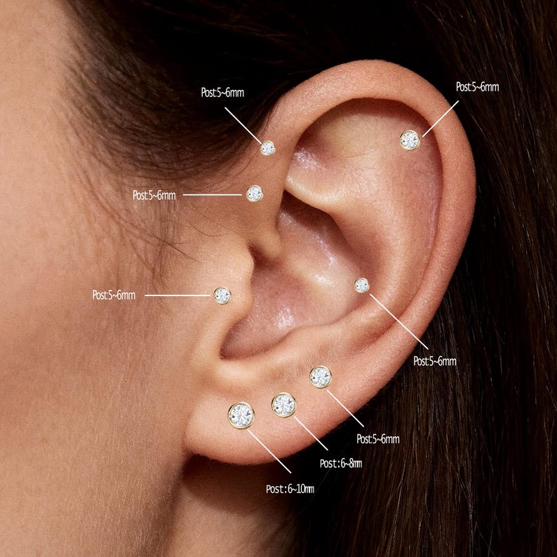May include: Close-up of an ear with multiple small, round stud earrings. The earrings are gold-toned with clear, sparkling stones. Text labels indicate post sizes ranging from 5-6mm to 6-10mm. The ear is set against a soft, neutral background.