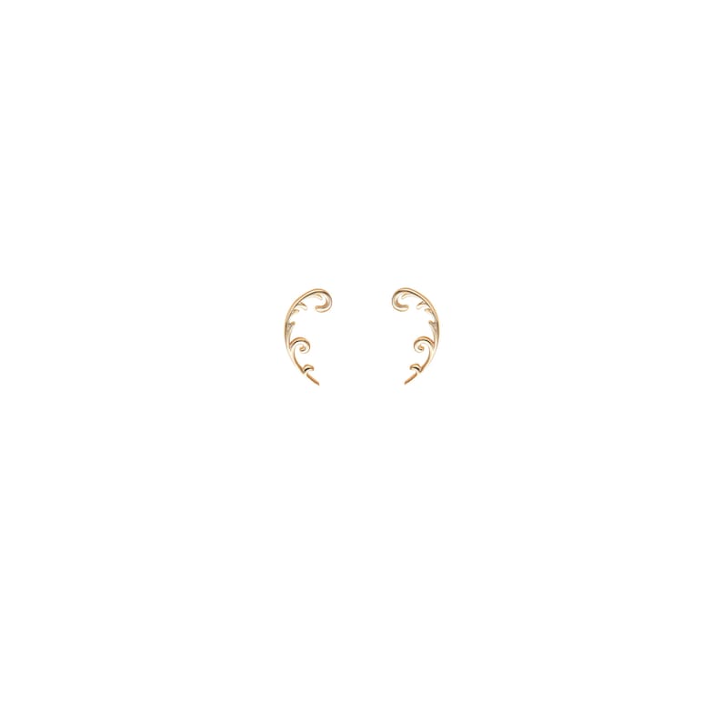 May include: A pair of gold-colored ear cuffs. Each cuff features a delicate, swirling vine design with small, subtle details. The ear cuffs curve gracefully, designed to be worn along the ear's edge, adding a touch of elegance.