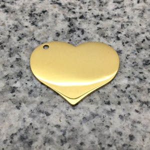 May include: A gold heart-shaped metal tag with a hole at the top for attaching a string or chain.