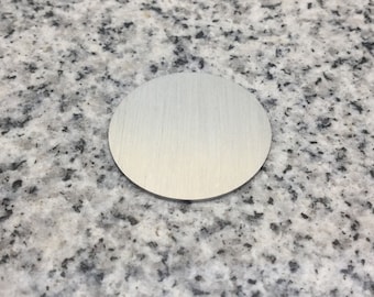 May include: A round, silver-colored metal disc with a brushed finish.