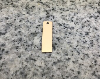 May include: A gold-colored metal tag with a rectangular shape and a hole at the top for hanging.