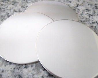 May include: Three white round coasters with a silver rim.
