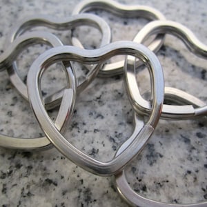 May include: A set of five silver heart-shaped keychains. The keychains are linked together and are made of metal.