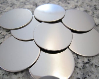 May include: A stack of round, silver metal discs. The discs are smooth and shiny.