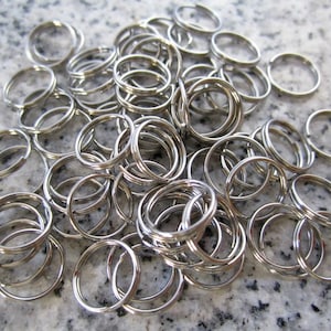 May include: A large pile of silver key rings. The key rings are all the same size and shape, and they are arranged in a random pattern.