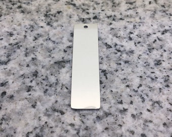 May include: A silver rectangular metal tag with a hole at the top.