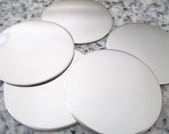 May include: Five round, silver-colored metal coasters. The coasters are smooth and reflective.