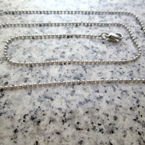 May include: A silver ball chain necklace with a lobster clasp.