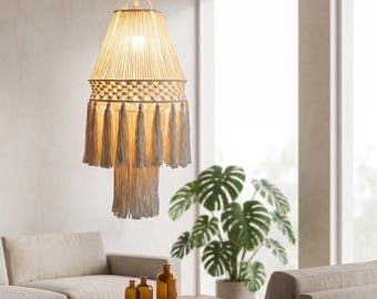 Puede incluir: Una lámpara colgante de macramé color crema con una pantalla cónica de intrincados patrones anudados, una banda ancha de flecos decorativos y una sección central de borlas colgantes que emite un brillo cálido y suave.