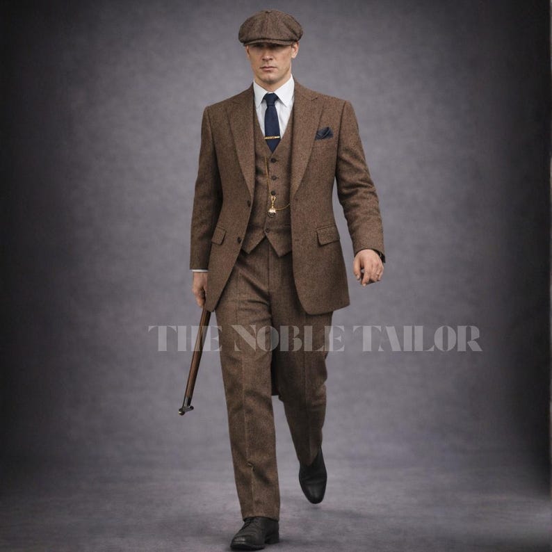 May include: A three-piece brown tweed suit with a matching flat cap, white shirt, and navy tie. The suit includes a blazer, vest, and trousers. A pocket square and a pocket watch are visible. The text "THE NOBLE TAILOR" is at the bottom.