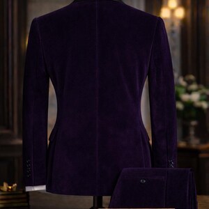 Puede incluir: Un traje formal de terciopelo morado expuesto en un maniqu&iacute;. El traje incluye una chaqueta con solapa de sat&eacute;n negro y pantalones a juego. El letrero frente al traje dice "The Noble Tailor".