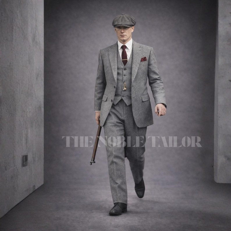 May include: A three-piece gray tweed suit with a matching flat cap, burgundy tie, and pocket square. The suit includes a vest and a tailored jacket. The image also shows a walking stick and the text "THE NOBLE TAILOR".