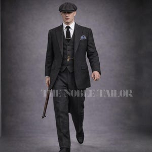 May include: A charcoal gray three-piece suit with a matching flat cap. The suit includes a blazer, vest, and trousers, paired with a white dress shirt and black tie. A pocket square and a pocket watch add detail. The text "THE NOBLE TAILOR" is visible.