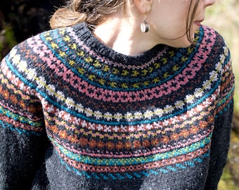 May include: A black sweater with a colorful Fair Isle pattern around the neckline. The sweater is made of a soft, textured yarn.