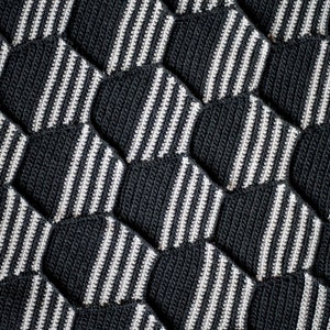 May include: A close-up of a black and white knitted fabric with a hexagonal pattern.