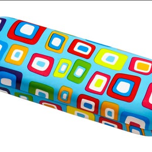 Könnte beinhalten: Ein rechteckiges Brillenetui mit einem lebendigen, farbenfrohen Design. Das Etui ist hellblau und mit einem Muster aus Quadraten und Rechtecken in Rot, Weiß, Gelb, Grün und Blau bedeckt. Das Etui ist geschlossen und scheint aus einem harten Material zu sein.