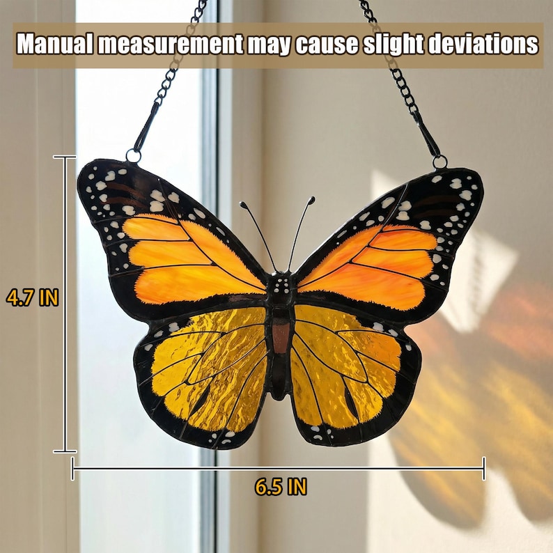 K&ouml;nnte beinhalten: Glasmalerei-Schmetterling-Suncatcher, 16,5 cm breit und 12 cm hoch. Der Schmetterling hat orange und gelbe Fl&uuml;gel mit schwarzen R&auml;ndern und wei&szlig;en Punkten. Er h&auml;ngt an einer schwarzen Kette. Text: Manuelle Messung kann leichte Abweichungen verursachen.