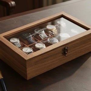 May include: A wooden watch display case with a glass top, showcasing several wristwatches. The case is rectangular with a hinged clasp. A glass of whiskey with ice and a smartphone are on the desk.