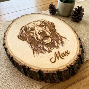 May include: A wooden, circular plaque with a detailed laser-engraved portrait of a dog. The dog's name, "Max," is elegantly scripted below the image. The plaque has a natural wood grain and a rough bark edge.