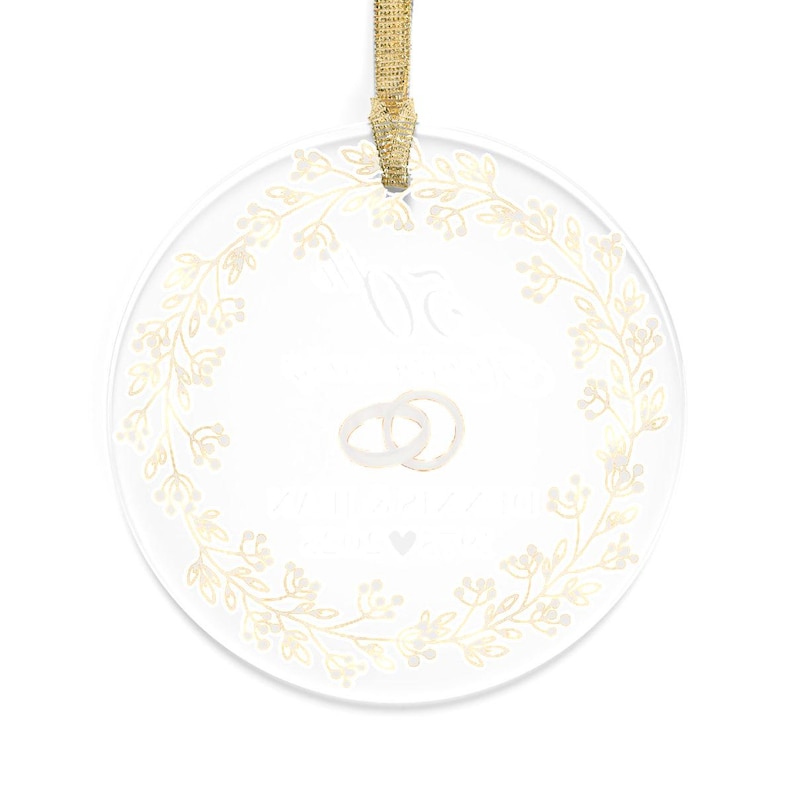 May include: Clear, round ornament with a gold floral wreath design. The ornament features two intertwined rings and text. A gold ribbon is attached for hanging. Ideal for weddings or anniversaries.