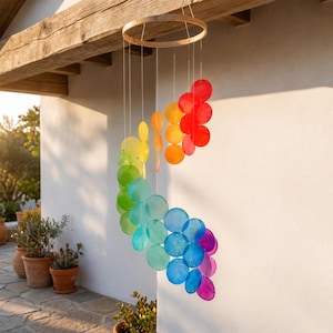 May include: A hanging mobile featuring a circular wooden frame with multiple translucent, circular discs in a vibrant rainbow gradient. The discs are suspended by thin strings, arranged in a cascading spiral pattern transitioning from red and orange to yellow, green, blue, and purple.