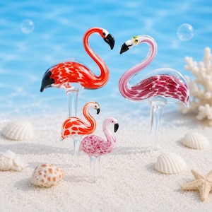 Peut inclure: Quatre figurines de flamants roses en verre, dans des tons de rouge et de rose, avec des becs noirs, reposent sur des tiges transparentes. Les flamants roses sont posés sur une surface sablonneuse avec des coquillages et une étoile de mer, sur fond bleu.