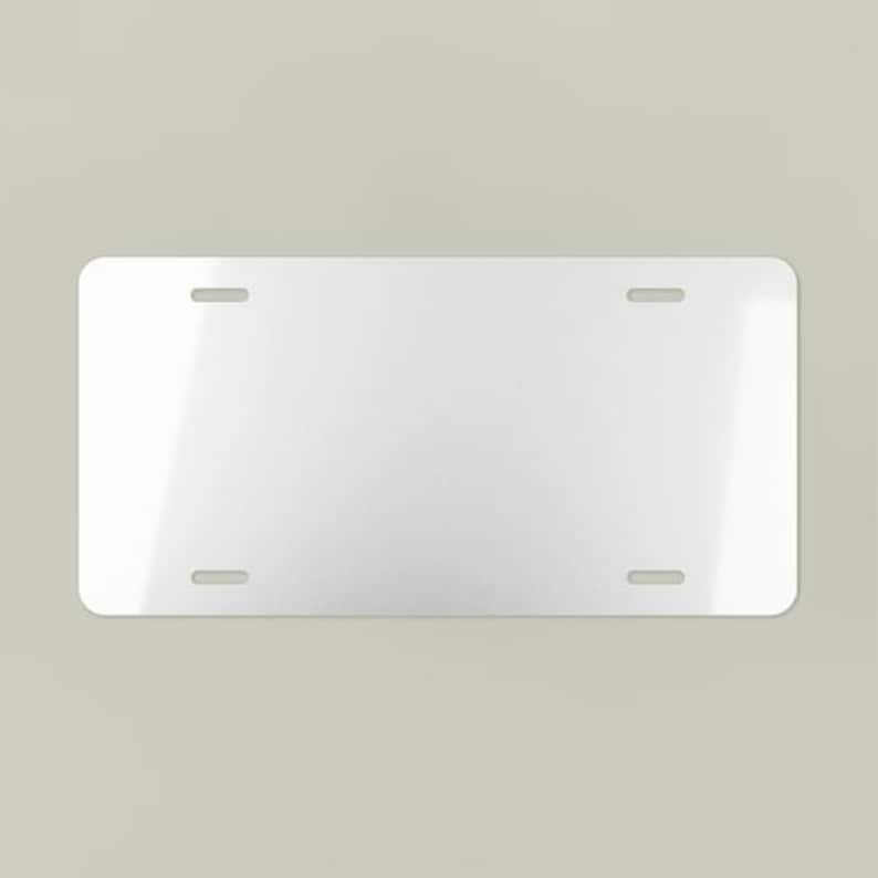 May include: A blank, rectangular license plate with rounded corners. The plate is white with four evenly spaced mounting holes. The surface has a slight sheen, reflecting ambient light.