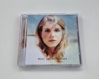 Może przedstawiać: Pudełko CD z fotografią kobiety z blond włosami. Na okładce widnieje napis "may jailer sirens". Pudełko CD jest wykonane z przezroczystego plastiku.