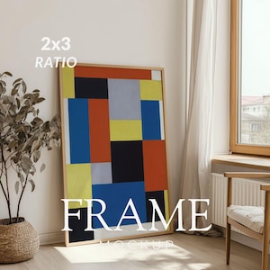May include: A framed artwork with a geometric design in red, blue, yellow, black, and gray. The frame is a light wood color. The text "2x3 RATIO" and "FRAME MOCKUP" are visible on the image.