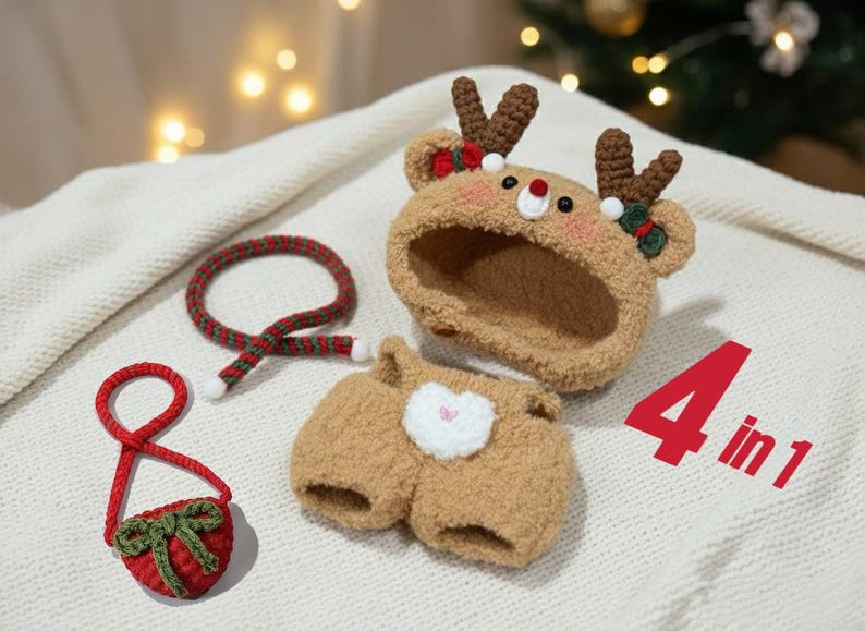 Close-up detail shot of the four-piece reindeer Christmas crochet outfit for 17cm dolls, featuring a decorated reindeer hood, brown overall outfit, red mini bag, and striped Christmas scarf displayed on a white surface.