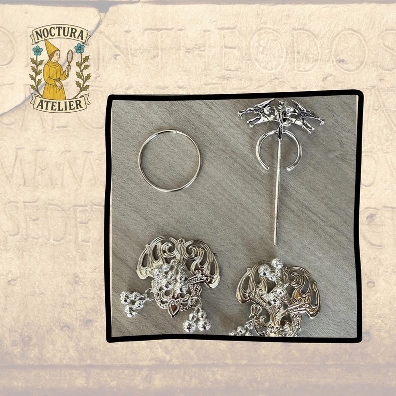 May include: A silver-toned metal set consisting of one plain circular ring, one penannular brooch featuring a dragon-like design, and two ornate filigree-style brooches with dangling spherical charms, all displayed together on a light surface.