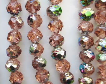 May include: Close-up of several strands of faceted, iridescent beads. The beads are a soft peach color with hints of green and blue iridescence. The beads have a textured, multi-faceted design.