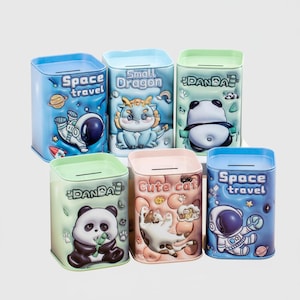 May include: Six colorful metal coin banks with various designs. The banks feature illustrations of a panda, a dragon, a cat, and an astronaut. Each bank has a slot for inserting coins and text that reads "Space travel", "Small Dragon", "Cute cat", and "Panda".