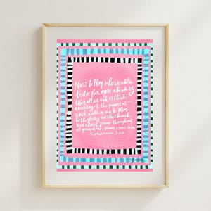 Könnte beinhalten: Gerahmter Kunstdruck mit einem hellen Holzrahmen. Das Kunstwerk zeigt eine rosa Mitte mit weißer Schrift, umgeben von schwarz-weißen Streifen, blauen Streifen und einem türkisfarbenen Rand. Der Text lautet "Now to Him who is able..."