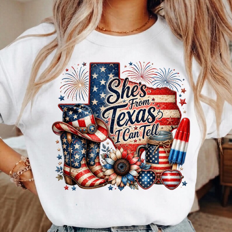 Pode incluir: Uma camisola branca de gola redonda com um gr&aacute;fico do estado do Texas com padr&otilde;es da bandeira americana, fogo de artif&iacute;cio, um chap&eacute;u de cowboy, uma bota, um girassol, um frasco, um gelado e &oacute;culos em forma de cora&ccedil;&atilde;o com o texto She's From Texas I Can Tell.