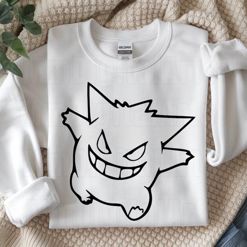 May include: White sweatshirt featuring a black outline of a cartoon character with a wide grin and pointed ears. The design is centered on the front of the crew neck sweatshirt. The sleeves are rolled up on either side of the sweatshirt.