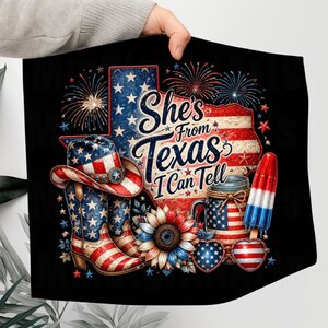 Pode incluir: Um quadrado de tecido preto com uma estampa gr&aacute;fica de um mapa em forma de Texas com padr&otilde;es da bandeira americana, fogos de artif&iacute;cio, um chap&eacute;u de cowboy, botas, um girassol, um pote, um picol&eacute; e &oacute;culos em forma de cora&ccedil;&atilde;o.