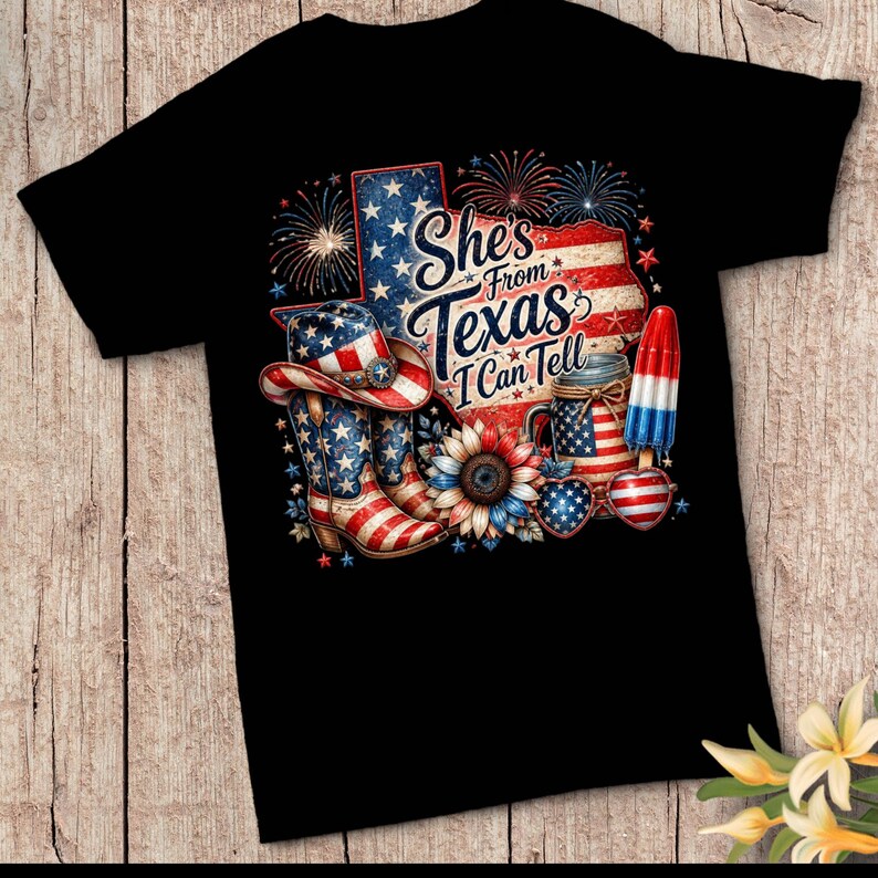 Pode incluir: Uma t-shirt preta com um gr&aacute;fico do estado do Texas com padr&otilde;es da bandeira americana, fogo de artif&iacute;cio, uma bota de cowboy, um girassol, um frasco, &oacute;culos em forma de cora&ccedil;&atilde;o e um gelado, com o texto She's From Texas I Can Tell.