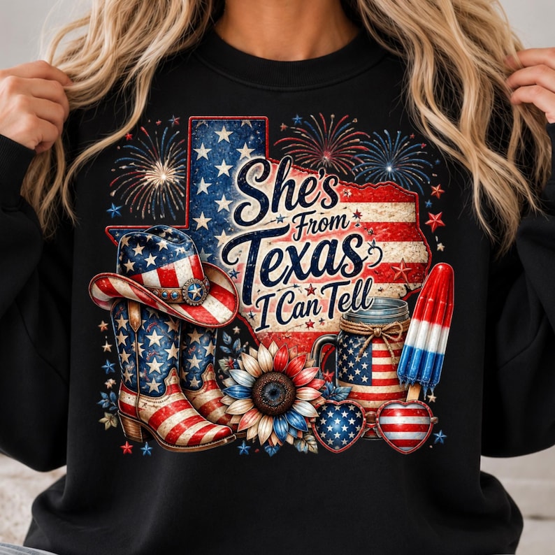 Pode incluir: Uma camisola preta com um gr&aacute;fico do estado do Texas com um padr&atilde;o de bandeira vermelha, branca e azul, fogo de artif&iacute;cio, um chap&eacute;u de cowboy, botas, um girassol, um frasco e um gelado. O texto diz: "She's From Texas I Can Tell."