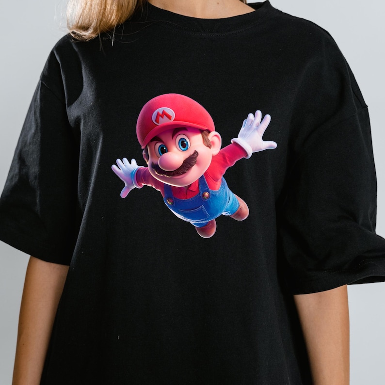 May include: Black t-shirt featuring a vibrant graphic of Mario in a dynamic pose. The character is depicted with his signature red cap, blue overalls, and white gloves. The design is centered on the shirt, creating a bold statement.