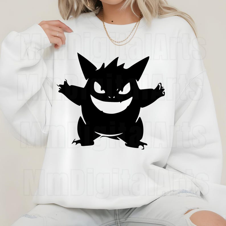 May include: White sweatshirt featuring a black graphic of a cartoon monster with a wide grin and spiky features. The design is centered on the front of the long-sleeved top. The sweatshirt is made of a soft material.