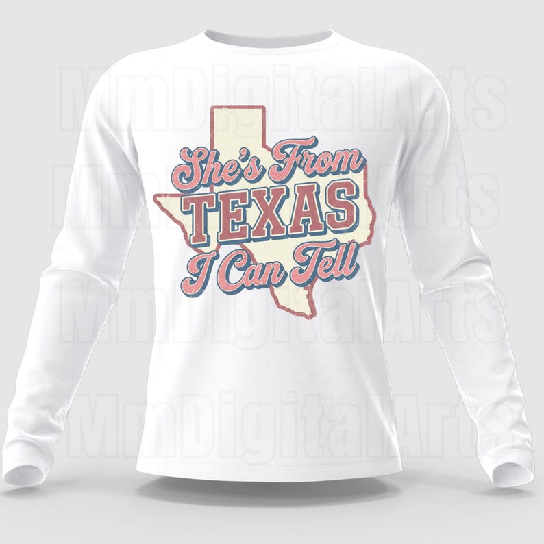 May include: White long-sleeve shirt with the text "She's From Texas I Can Tell" in a retro design. The text is in pink and blue, with a Texas state outline. A casual, comfortable top.
