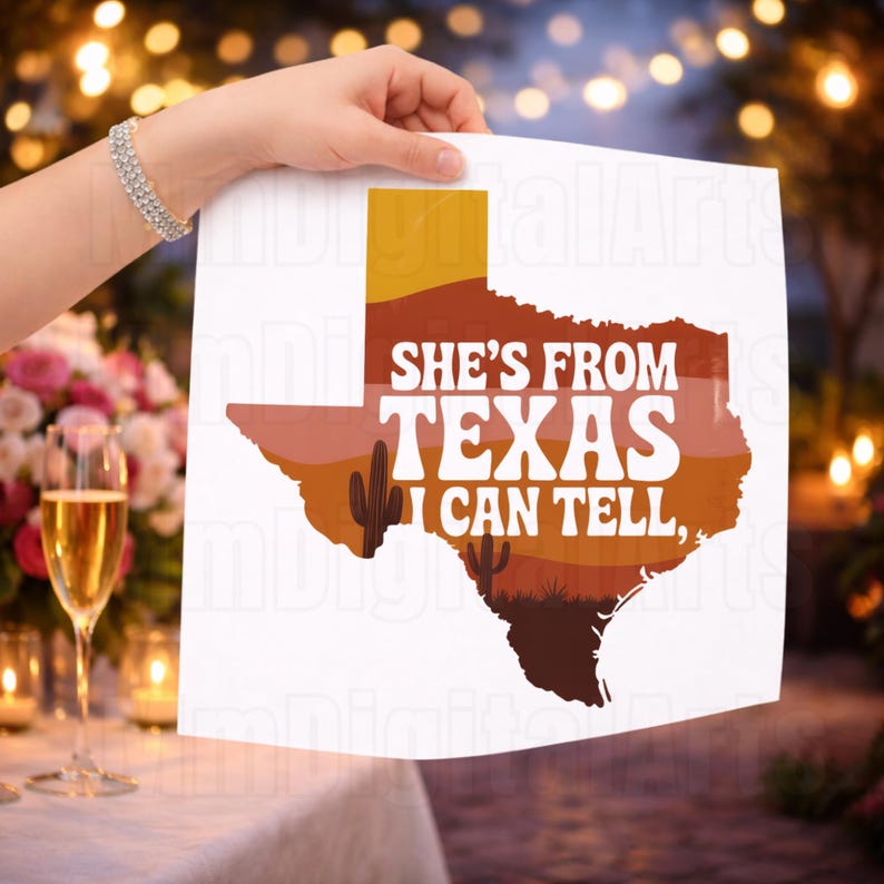 May include: A white print featuring the outline of Texas in shades of brown and orange, with the text "SHE'S FROM TEXAS I CAN TELL." A cactus silhouette is included. The print is held up by a person.