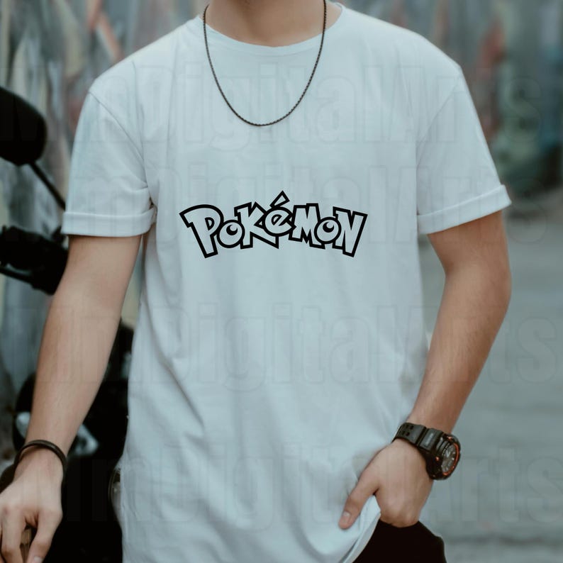May include: White t-shirt with the word "Pok&eacute;mon" in black, stylized lettering. The shirt is short-sleeved and appears to be made of cotton. A black necklace and watch are also visible.