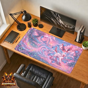 Op de afbeelding: Een grote rechthoekige bureaumat met een Sylveon-ontwerp. De mat heeft een kleurrijk ontwerp met roze, blauwe en paarse tinten. De tekst "ObsidianMousepad" is zichtbaar linksonder.