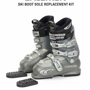 May include: A pair of gray Salomon ski boots with black accents and silver buckles, along with two black sole replacement pieces. The boots have the text "SALOMON" and "SKI BOOT SOLE REPLACEMENT KIT" printed on them.