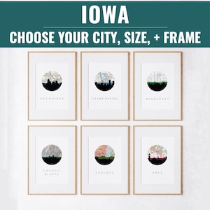 May include: Six framed prints featuring city skyline silhouettes with map details. The prints showcase Des Moines, Cedar Rapids, Bondurant, Council Bluffs, Dubuque, and Ames. The text "IOWA" and "CHOOSE YOUR CITY, SIZE, + FRAME" are at the top.