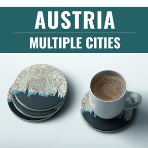 May include: Coasters with a map design and a dark blue skyline. The coasters are round and stacked, with one coaster holding a white mug of coffee. The text "AUSTRIA MULTIPLE CITIES" is at the top.